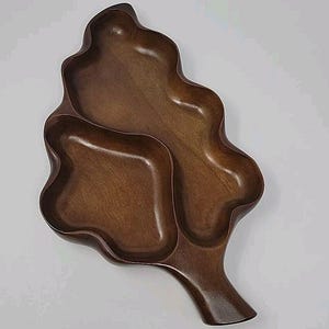 May include: A dark brown wooden serving tray shaped like a leaf with three separate compartments.