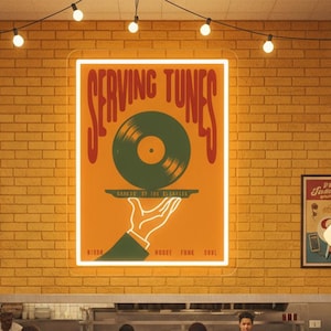 May include: A retro diner scene with people eating burgers and fries. A large sign reads "Serving Tunes" with a vinyl record graphic. The diner has red and white booths, a brick wall, and vintage posters.