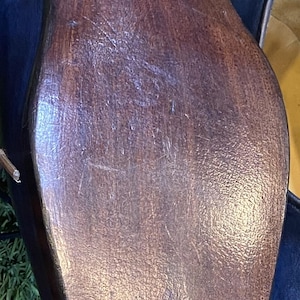 K&ouml;nnte beinhalten: Nahaufnahme der Sohle eines dunkelblauen Lederschuhs. Die Sohle besteht aus braunem Holz mit sichtbarer Maserung und kleinen, gleichm&auml;&szlig;ig verteilten Stiften. Der Schuh steht auf einer gr&uuml;nen Oberfl&auml;che.