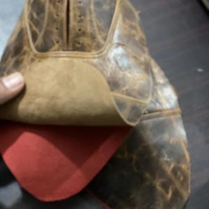 K&ouml;nnte beinhalten: Nahaufnahme eines braunen Lederschuhs mit Used-Look. Das Innere des Schuhs ist mit rotem Stoff gef&uuml;ttert. Das Leder weist sichtbare Abnutzungserscheinungen auf, was auf eine Vintage- oder rustikale &Auml;sthetik hindeutet. Der Schuh ist teilweise ge&ouml;ffnet.