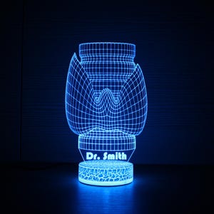 May include: A blue 3D printed night light shaped like a jar with a flower design. The base of the night light has the text "Dr. Smith" printed on it.