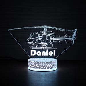 May include: A white LED night light shaped like a helicopter with the name "Daniel" underneath. The light is on a textured base.
