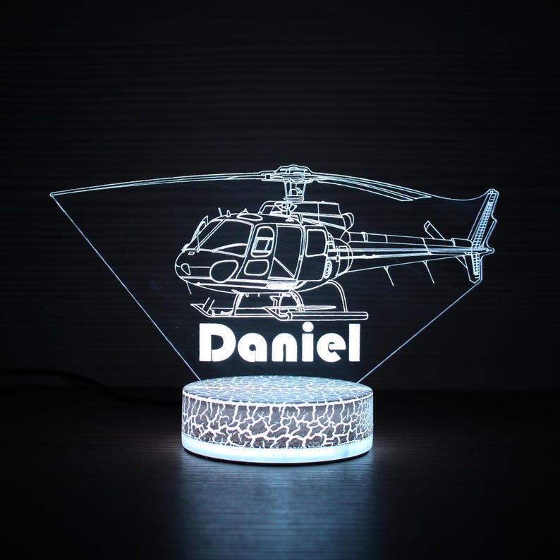 May include: A white LED night light shaped like a helicopter with the name "Daniel" underneath. The light is on a textured base.