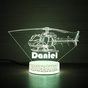 May include: A white LED night light shaped like a helicopter with the name "Daniel" underneath. The light is on a textured base.