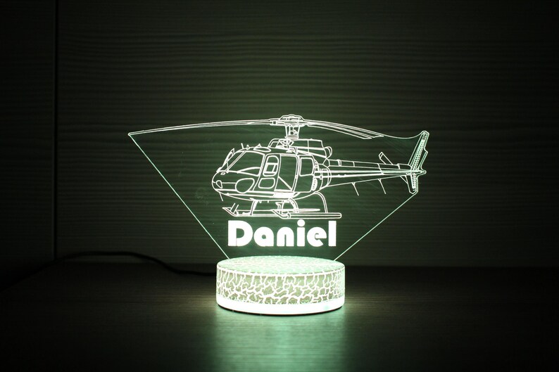 May include: A white LED night light shaped like a helicopter with the name "Daniel" underneath. The light is on a textured base.