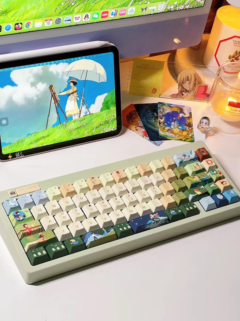 K&ouml;nnte beinhalten: Eine hellgr&uuml;ne mechanische Tastatur mit benutzerdefinierten Tastenkappen, die Illustrationen aus dem Animationsfilm 'Kikis kleiner Lieferservice' zeigen. Die Tastenkappen sind in verschiedenen Gr&uuml;nt&ouml;nen, Blau- und Beiget&ouml;nen gehalten, mit einigen wei&szlig;en Tasten. Die Tastatur hat einen hellgr&uuml;nen Rahmen und eine wei&szlig;e Basis.