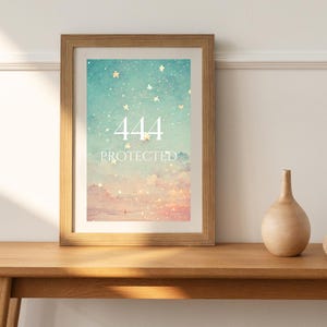 Könnte beinhalten: Ein gerahmter Kunstdruck mit einem himmlischen Design in Türkis- und Rosatönen. Der Druck zeigt die Zahlen "444" über dem Wort "PROTECTED" in Weiß. Das Kunstwerk ist in einem hellbraunen Holzrahmen gefasst und liegt auf einem Holztisch.
