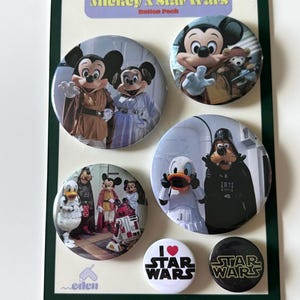 May include: A button pack featuring six round buttons with images of Disney characters in Star Wars themed costumes. The buttons are on a cream-colored backing with a green border. Text on the buttons includes "Mickey X Star Wars Button Pack" and "I Star Wars".