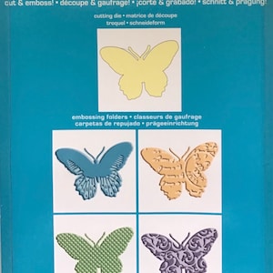 May include: A package of four butterfly-shaped metal dies for use with a die-cutting machine. The dies are shown in four different designs: blue, orange, green, and purple. The package is labeled "Cuttlebug" and "Butterflies".