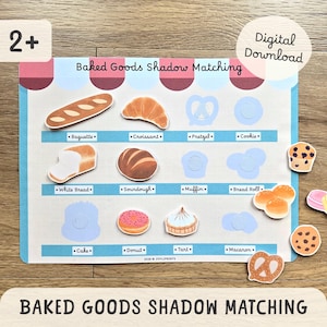 May include: A colorful educational game featuring baked goods. The game board has illustrations of various baked items like a baguette, croissant, and donut. The game is titled "Baked Goods Shadow Matching" and is suitable for ages 2+.