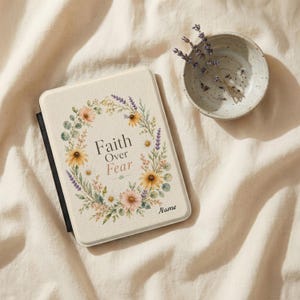 May include: A rectangular e-reader cover with a cream-colored surface featuring a floral wreath of sunflowers, lavender, and greenery. The text Faith Over Fear is printed in the center, with the word Name in the bottom right corner.