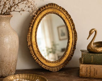 Espejo de pared ovalado italiano vintage con detalles dorados, decoración estilo Hollywood Regency.