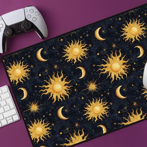 May include: A black mouse mat with a repeating pattern of gold suns and moons on a dark blue background. The pattern is reminiscent of a celestial night sky.