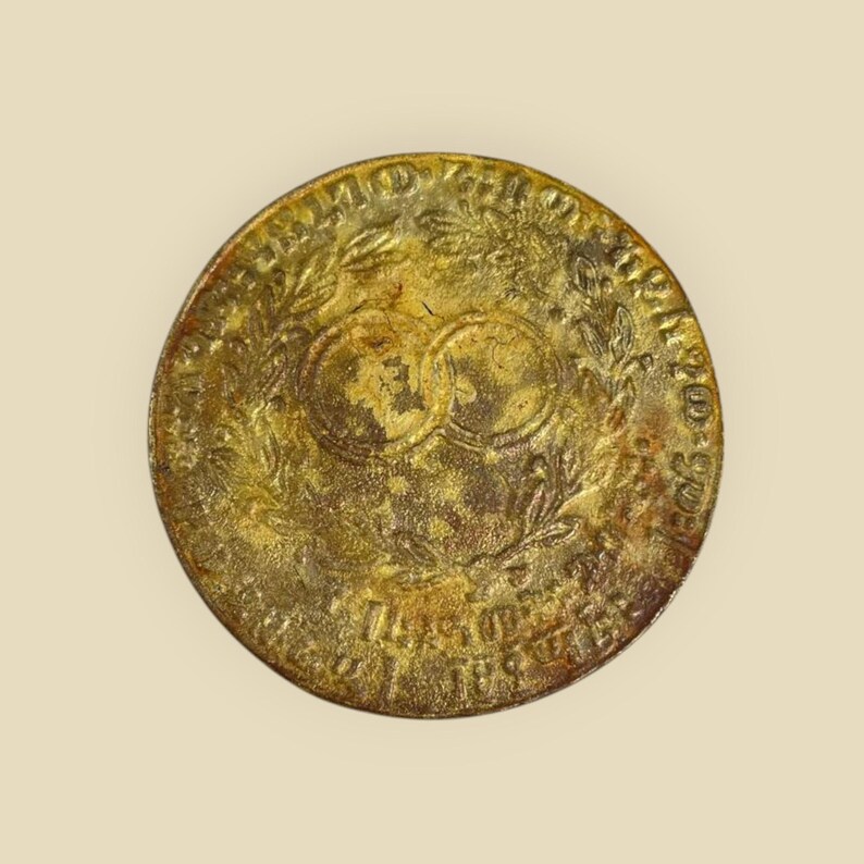 May include: A gold-colored coin with a wreath of leaves and the text "Anno Domini 1793" around the edge. The center of the coin features two intertwined circles.