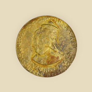 May include: A gold-colored coin with a profile of a woman wearing a crown on the obverse. The coin has text around the edge, including "VICTORIA REGINA" and "1837 - 1861".