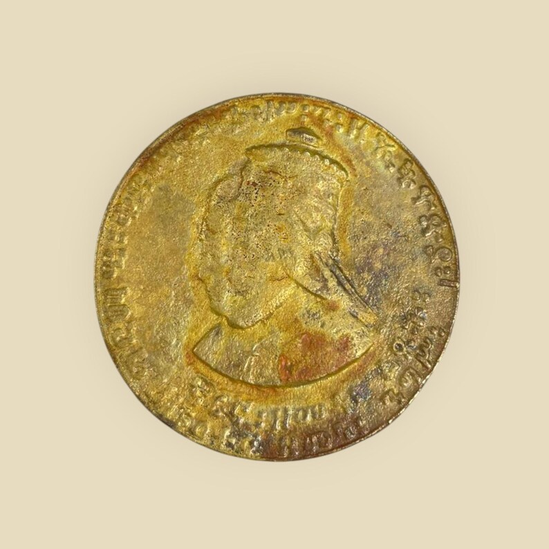 May include: A gold-colored coin with a profile of a woman wearing a crown on the obverse. The coin has text around the edge, including "VICTORIA REGINA" and "1837 - 1861".