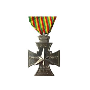 Puede incluir: Una medalla de plata con una estrella en el centro y el texto "1984" en la parte superior. La medalla est&aacute; en una cinta verde, amarilla y roja.