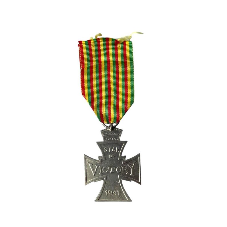 Puede incluir: Una medalla de plata de la Estrella de la Victoria con una cinta rayada roja, amarilla y verde. La medalla presenta una cruz con las palabras "STAR of VICTORY" y "1941" inscritas en ella.