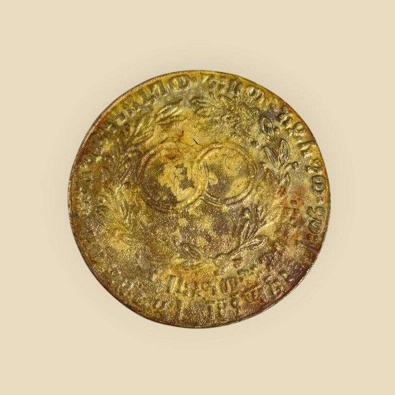 May include: A gold-colored coin with a wreath of leaves and the text "Anno Domini 1810" around the edge. The center of the coin features two overlapping circles.