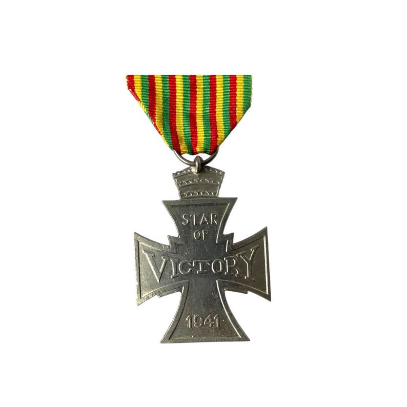 Puede incluir: Una medalla de plata de la Estrella de la Victoria con una cinta rayada roja, amarilla y verde. La medalla presenta una cruz con las palabras "Star of Victory" y "1941" inscritas en ella.