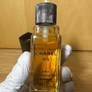 Puede incluir: Una botella vintage de Chanel N&ordm;5 Eau de Toilette. La botella de vidrio transparente contiene un l&iacute;quido de color dorado y presenta un tap&oacute;n negro. El logotipo de Chanel y la informaci&oacute;n del producto est&aacute;n impresos en letras doradas.