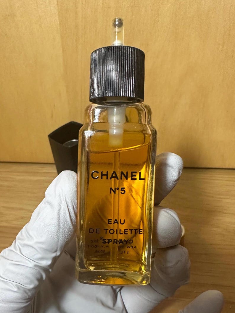 Puede incluir: Una botella vintage de Chanel N&ordm;5 Eau de Toilette. La botella de vidrio transparente contiene un l&iacute;quido de color dorado y presenta un tap&oacute;n negro. El logotipo de Chanel y la informaci&oacute;n del producto est&aacute;n impresos en letras doradas.
