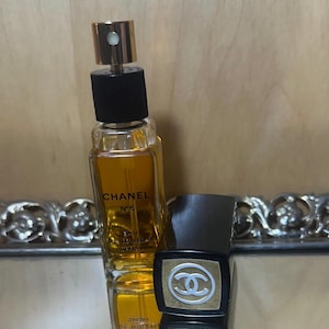 Puede incluir: Una botella de Chanel No. 5 Eau de Toilette Spray con tap&oacute;n dorado y base negra. La botella contiene un l&iacute;quido dorado. Junto a ella, un estuche negro y dorado con el logo de Chanel.