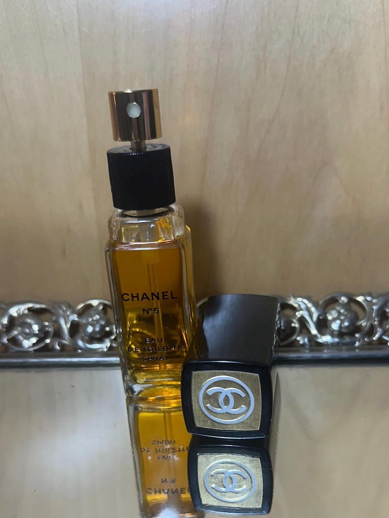 Puede incluir: Una botella de Chanel No. 5 Eau de Toilette Spray con tap&oacute;n dorado y base negra. La botella contiene un l&iacute;quido dorado. Junto a ella, un estuche negro y dorado con el logo de Chanel.