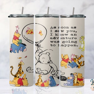 May include: A white tumbler with a Winnie the Pooh design. The tumbler features Winnie the Pooh, Piglet, Tigger, and Eeyore. The text on the tumbler reads "As soon as I saw you, I knew an adventure was going to happen."