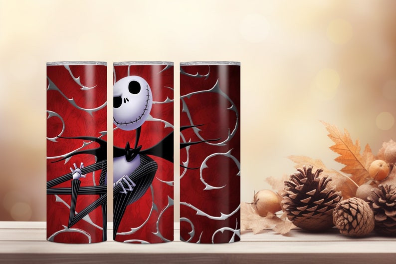 May include: A set of three stainless steel tumblers featuring a design of Jack Skellington from The Nightmare Before Christmas. The tumblers have a red background with silver thorn-like accents. Jack is depicted in his classic black and white suit.