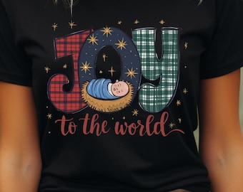 May include: Black t-shirt with the words "JOY to the world" in a festive design. The letters are filled with plaid patterns and a starry night sky. A baby in a manger is in the center of the "O".