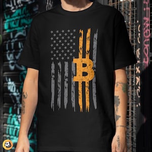 May include: Black t-shirt featuring a distressed American flag design with a Bitcoin symbol in the center. The flag incorporates gray and orange stripes, with the Bitcoin symbol in orange. The shirt has a crew neck and short sleeves.