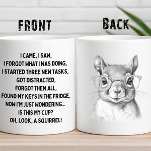 May include: White ceramic coffee mug with a black and white illustration of a squirrel wearing glasses. The text on the mug reads "I came, I saw, I forgot what I was doing, I started three new tasks, got distracted, forgot them all, found my keys in the fridge, now I'm just wondering... is this my cup? Oh, look, a squirrel!"