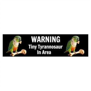 以下が含まれることがあります： 「WARNING Tiny Tyrannosaur In Area」と書かれた白い文字の黒い長方形の看板。2羽の緑、赤、黄色のオウムが骨の形をした物体にとまっています。オウムはくちばしに食べ物を持っています。