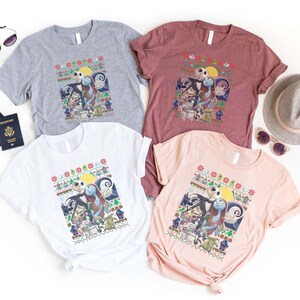 May include: Four t-shirts featuring a Christmas-themed design with Jack Skellington and Sally from The Nightmare Before Christmas. The shirts are in grey, maroon, white, and pink.