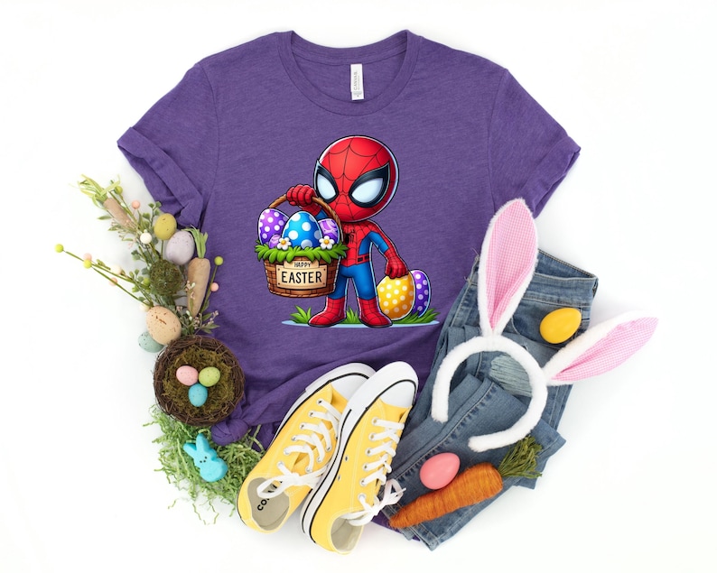 以下が含まれることがあります： パープルカラーのTシャツに、イースターエッグの入ったバスケットを持ったスパイダーマンの漫画が描かれています。バスケットには「ハッピーイースター」の文字が書かれています。