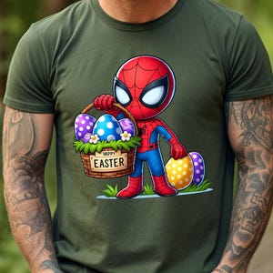 以下が含まれることがあります： 緑色のTシャツに、イースターエッグの入ったバスケットを持ったスパイダーマンの漫画の画像が描かれています。バスケットには「ハッピーイースター」と書かれています。