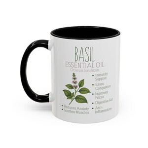 May include: White ceramic mug with a black handle and interior. The mug features the text "BASIL ESSENTIAL OIL" with a botanical illustration of basil and a list of benefits including "Reduces Anxiety" and "Immunity Support".