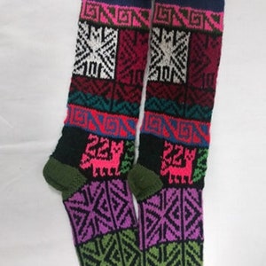 May include: Pair of colorful knitted knee-high socks with geometric patterns and a llama design. The socks are black, pink, green, blue, red, and white.