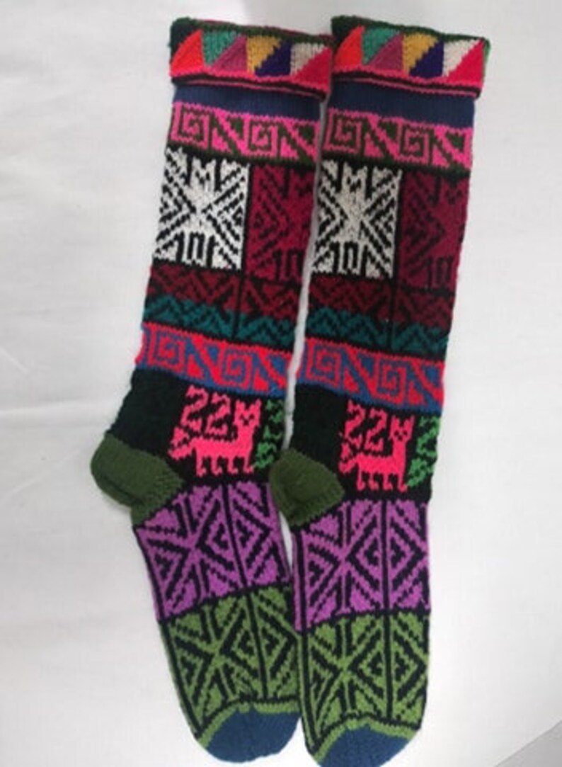 May include: Pair of colorful knitted knee-high socks with geometric patterns and a llama design. The socks are black, pink, green, blue, red, and white.