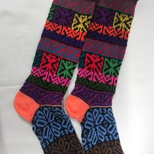 May include: A pair of colorful knitted knee-high socks with geometric patterns in shades of pink, blue, green, yellow, and black.