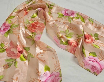 May include: A peach-colored silk scarf with a floral pattern of pink and orange roses and green leaves.