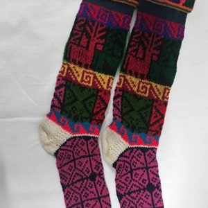 May include: A pair of colorful knitted knee-high socks with geometric and animal patterns. The socks are made of wool and have a white cuff.