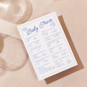 May include: A blue and white printable baby trivia game with questions about babies and their development. The questions are written in a blue font and the answers are in a black font. The game is perfect for a baby shower or a gender reveal party.
