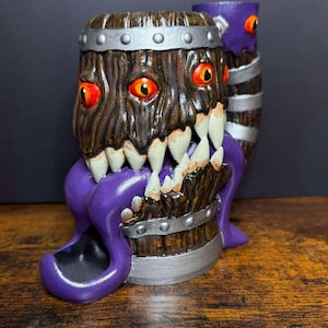 May include: A wooden barrel with a purple tentacle-like mouth and three red eyes. The barrel has silver bands around it and is painted to look like wood. The tentacle mouth has a small black bowl inside.