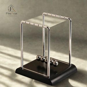 Op de afbeelding: Een Newton's cradle bureau-speelgoed met een zwarte basis en een gepolijst chromen frame. Vijf glanzende metalen bollen hangen in een rij en demonstreren de overdracht van momentum. Het bovenste frame heeft een heldere, rechthoekige plank. Het logo "FineXcut" staat linksboven.
