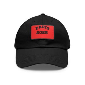 Puede incluir: Gorra de béisbol negra con un parche rojo que dice "PARIS 2025" en letras negras.