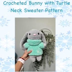 Puede incluir: Un conejito gris de crochet con un suéter de cuello alto azul turquesa. El conejito tiene una nariz rosa y ojos negros.