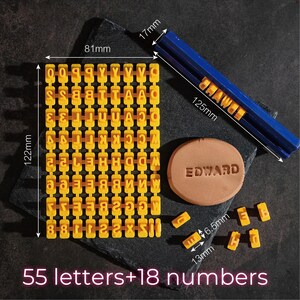 May include: A yellow letter and number stamp set with a blue handle, and a clay circle stamped with the name "EDWARD". The set includes 55 letters and 18 numbers. The letter grid is 122mm tall and 81mm wide.