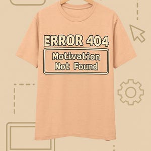 Op de afbeelding: Een perzikkleurig t-shirt met de tekst "ERROR 404 Motivation Not Found" in een zwart omlijnde doos. Het shirt hangt aan een houten hanger tegen een lichtbruine achtergrond met grafische elementen.